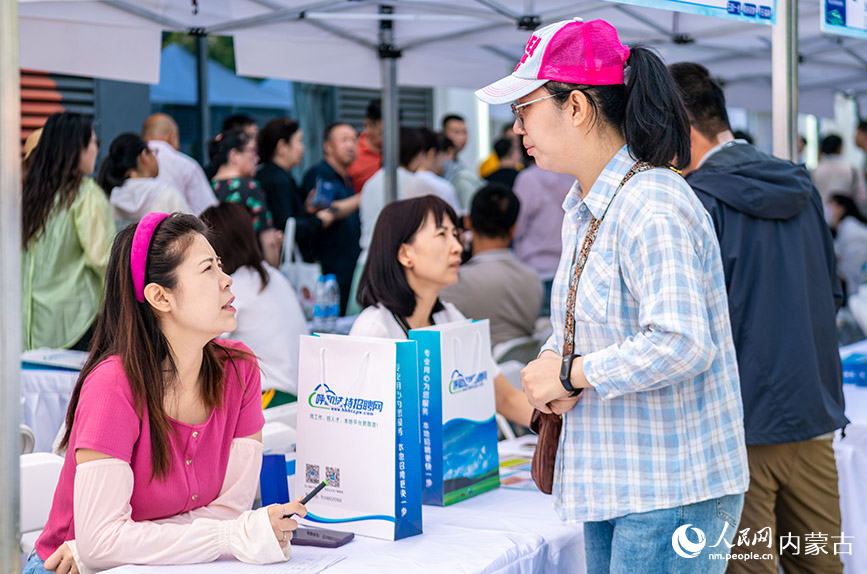 5月25日，求职者在呼和浩特市玉泉区户外大型线下招聘会现场与用人单位交流。丁根厚摄