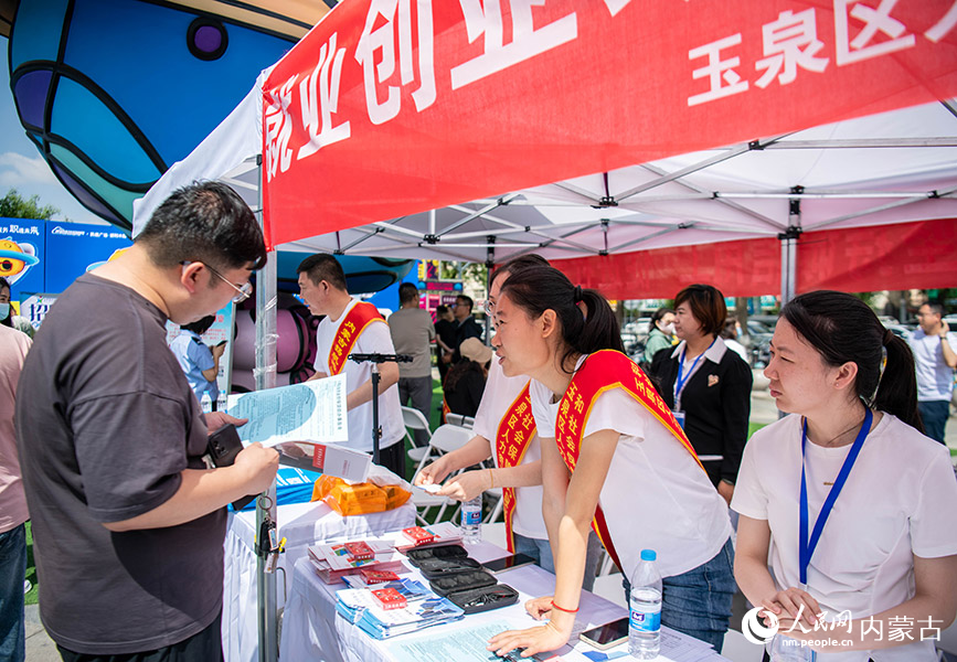 5月25日，工作人员在呼和浩特市玉泉区户外大型线下招聘会现场为参会者解读个人创业担保贷款的相关知识。丁根厚摄