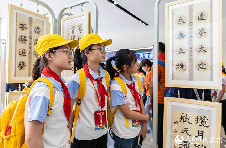 各族少年儿童代表在内蒙古呼和浩特市锡林南路小学参观校园“铸牢中华民族共同体意识”书画展。丁根厚摄