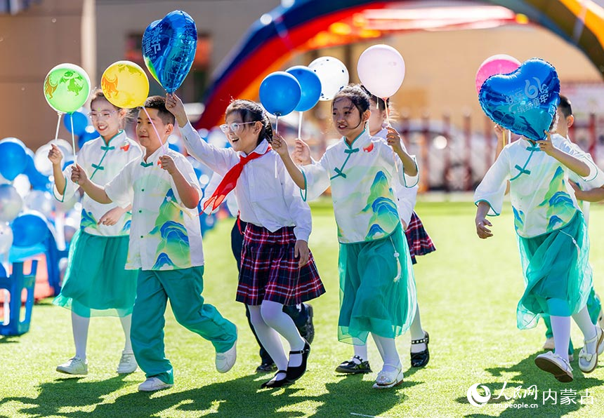 呼和浩特市玉泉區西菜園小學學生在慶“六一”主題活動現場開心地留影。丁根厚攝