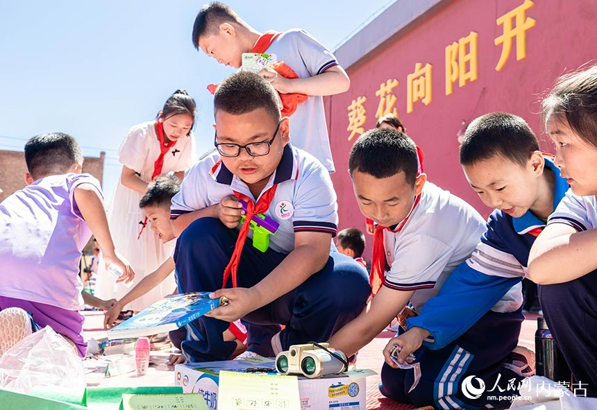 呼和浩特市玉泉区西菜园小学学生在亲子跳蚤市场欢乐淘活动现场选购物品。丁根厚摄