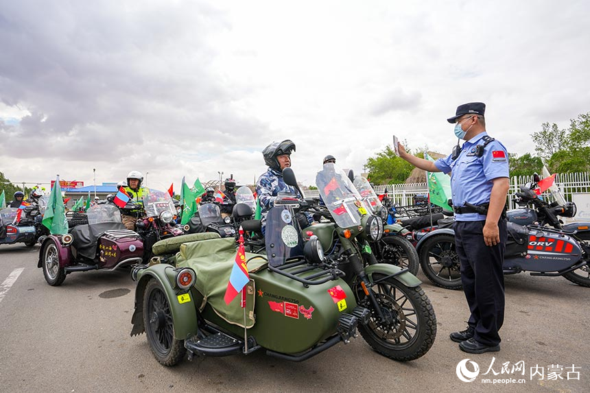 二连出入境边防检查站移民管理警察查验摩托车自驾旅游团成员通关证件。杨金烨摄