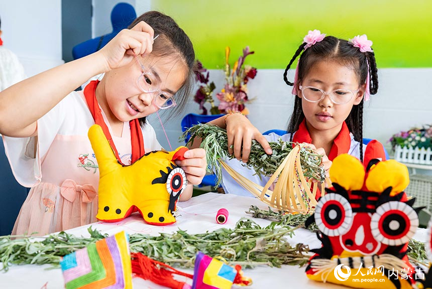 呼和浩特市玉泉区通顺街小学学生在“我们的节日·端午”主题活动上缝制布老虎。丁根厚摄