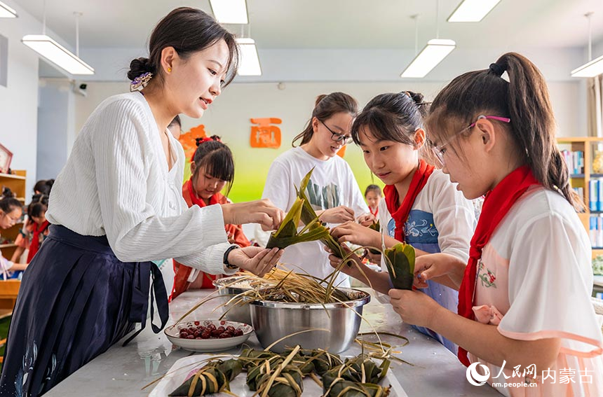 呼和浩特市玉泉区通顺街小学师生在“我们的节日·端午”主题活动上包粽子。丁根厚摄