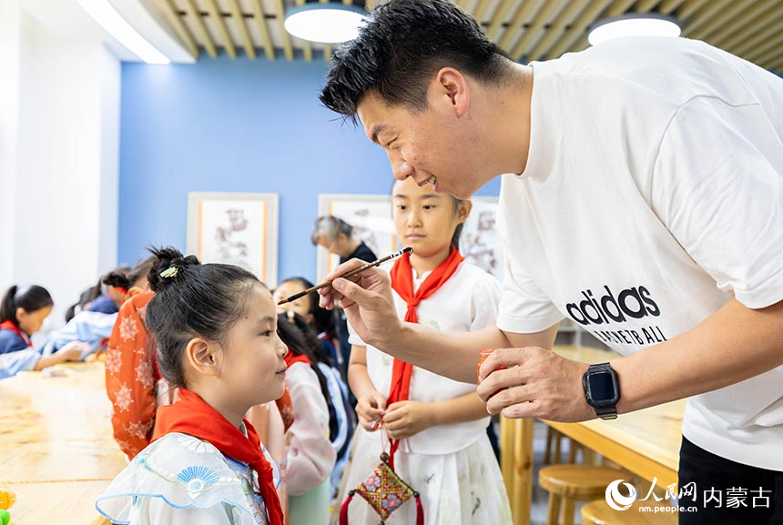 呼和浩特市玉泉区南柴火市街小学老师在用雄黄酒为孩子们额头上书写王字。丁根厚摄