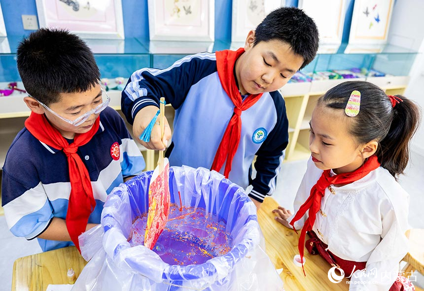 呼和浩特市玉泉區南柴火市街小學學生在“我們的節日·端午”主題活動上制作漆扇。丁根厚攝