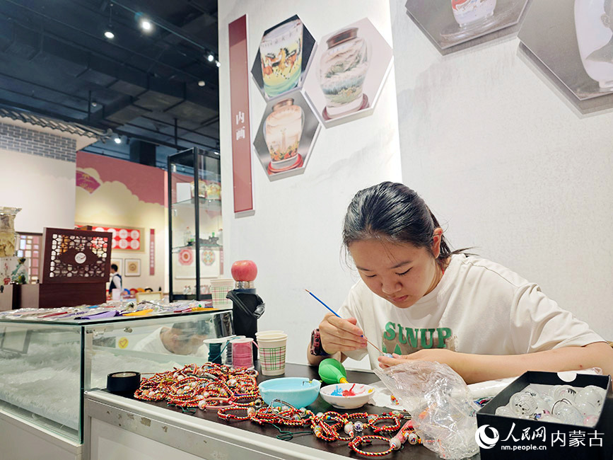 北疆非物质文化遗产精品展现场，游客正在体验内画技艺。人民网记者 刘艺琳摄