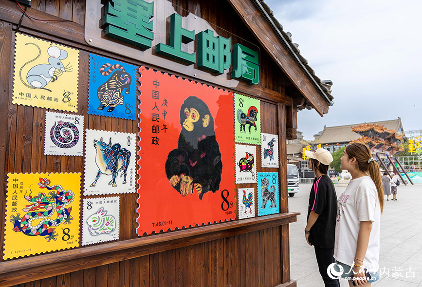 6月18日，游客在呼和浩特市玉泉区塞上老街旅游休闲街区“塞上主题邮局”前观看邮票宣传品。丁根厚摄