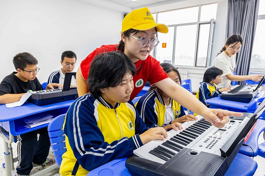 大学生志愿者在呼和浩特市第十二中学乡村少年宫指导学员们演奏电子琴。丁根厚摄