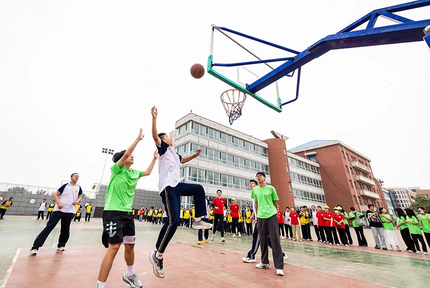 大学生志愿者在呼和浩特市第十二中学乡村少年宫和学员们进行篮球比赛。丁根厚摄