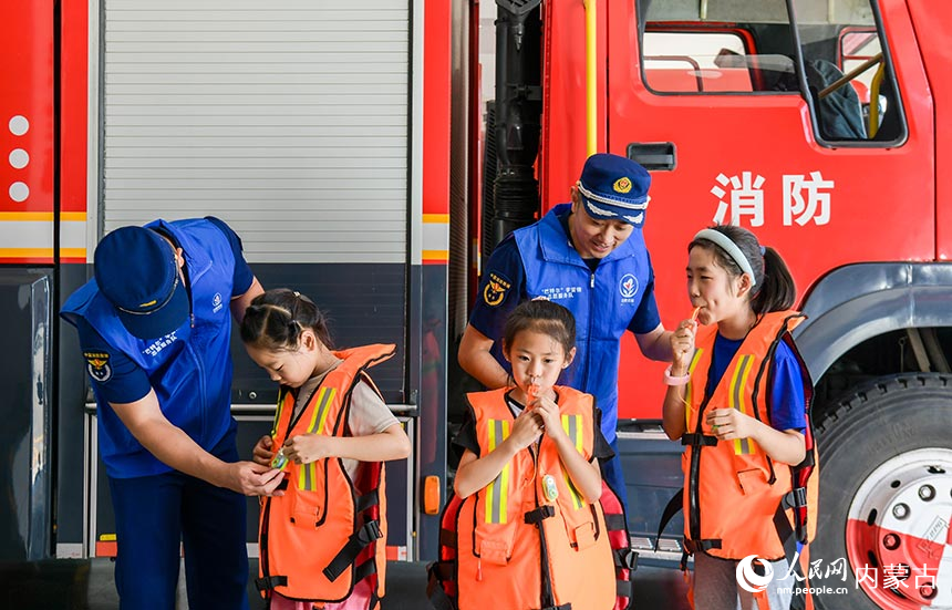 孩子们在呼和浩特市玉泉区南二环路消防救援站体验穿戴救生衣马甲。丁根厚摄