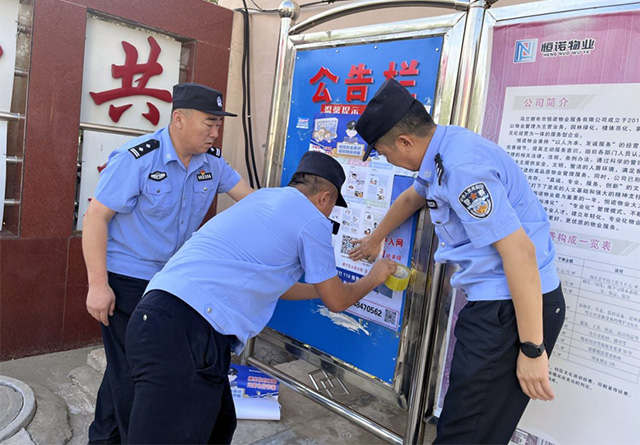 民警在小区里张贴反诈宣传海报。