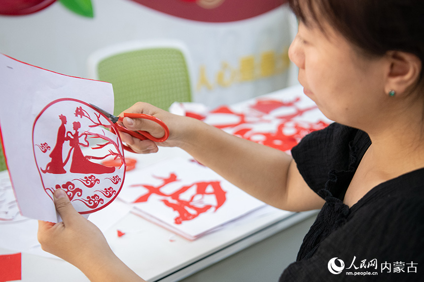 呼和浩特市玉泉区清泉街社区居民在“我们的节日·七夕”主题活动现场制作以“浪漫七夕”为主题的剪纸作品。丁根厚摄