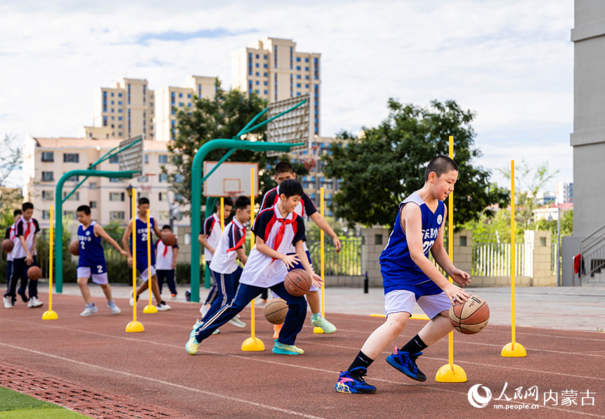 呼和浩特市玉泉区石东路小学学生在体育课上进行篮球绕桩运球比赛。丁根厚摄