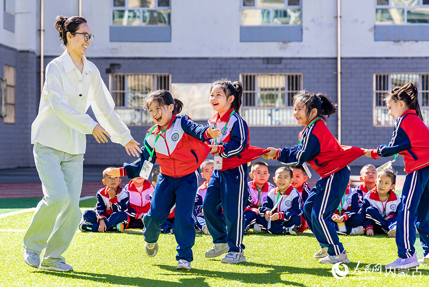 呼和浩特市玉泉区石东路小学一年级师生在大课间玩“老鹰抓小鸡”游戏。丁根厚摄