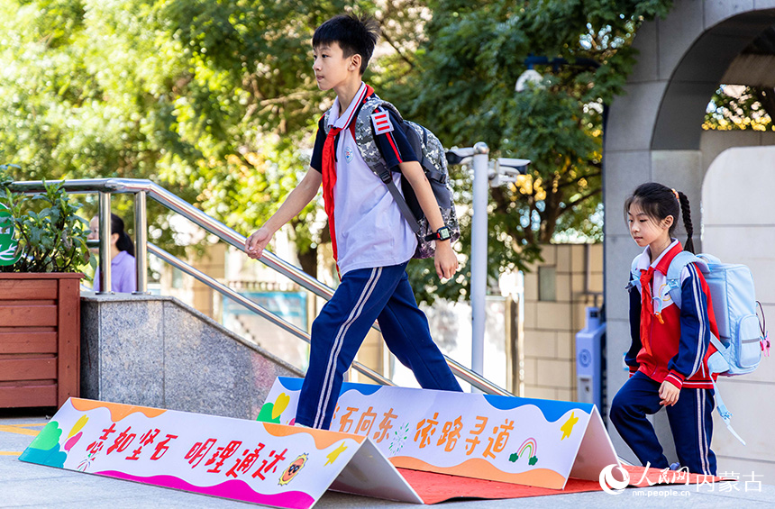 呼和浩特市玉泉区石东路小学学生跨越励志牌进入校园。丁根厚摄