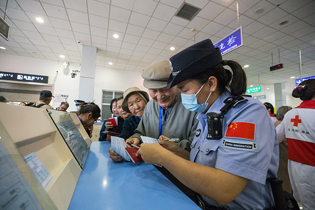 图4：2024年9月9日，二连出入境边防检查站移民管理警察帮助旅客填写外国人入境登记卡。