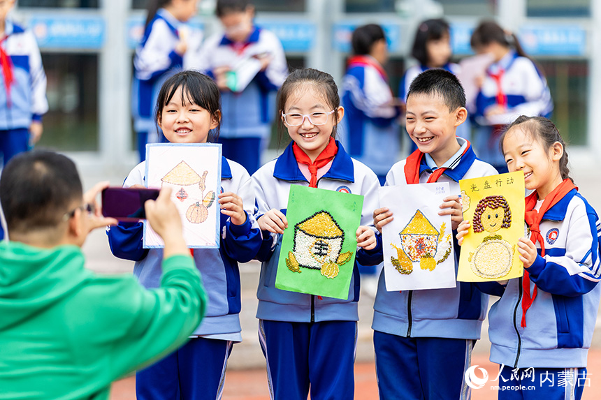 呼和浩特市玉泉区通顺街小学学生展示自己绘制的粮食画。丁根厚摄