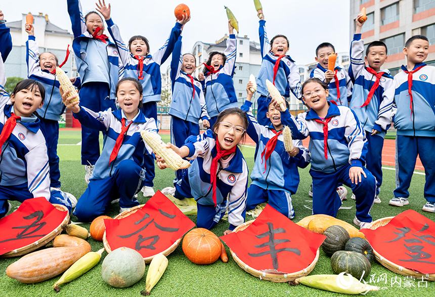 呼和浩特市玉泉区通顺街小学学生在剥玉米皮比赛现场欢呼。丁根厚摄