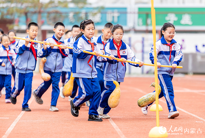 呼和浩特市玉泉區通順街小學學生在進行運瓜繞樁跑接力賽。丁根厚攝