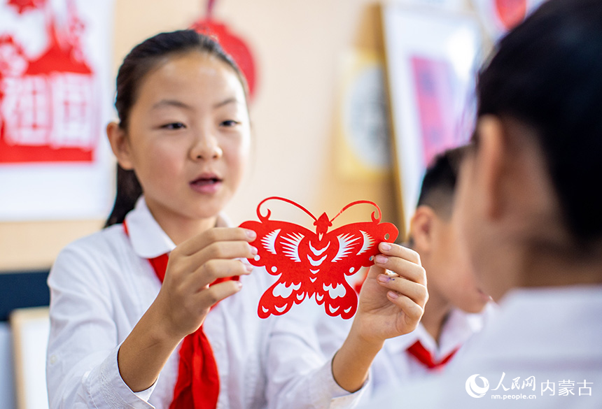 呼和浩特市玉泉区恒昌店巷小学五里营校区的学生在制作迎国庆主题的剪纸作品。丁根厚摄