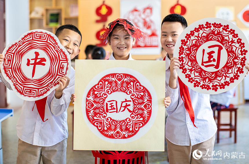 呼和浩特市玉泉区恒昌店巷小学五里营校区的学生在展示迎国庆主题剪纸作品。丁根厚摄