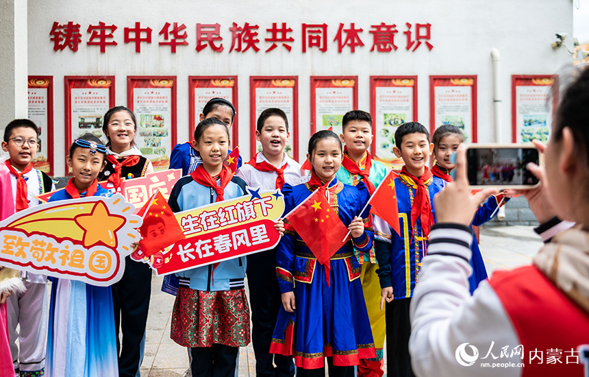 呼和浩特市玉泉区南柴火市街小学师生在“童心颂祖国 欢歌迎国庆”主题活动现场打卡拍照。丁根厚摄