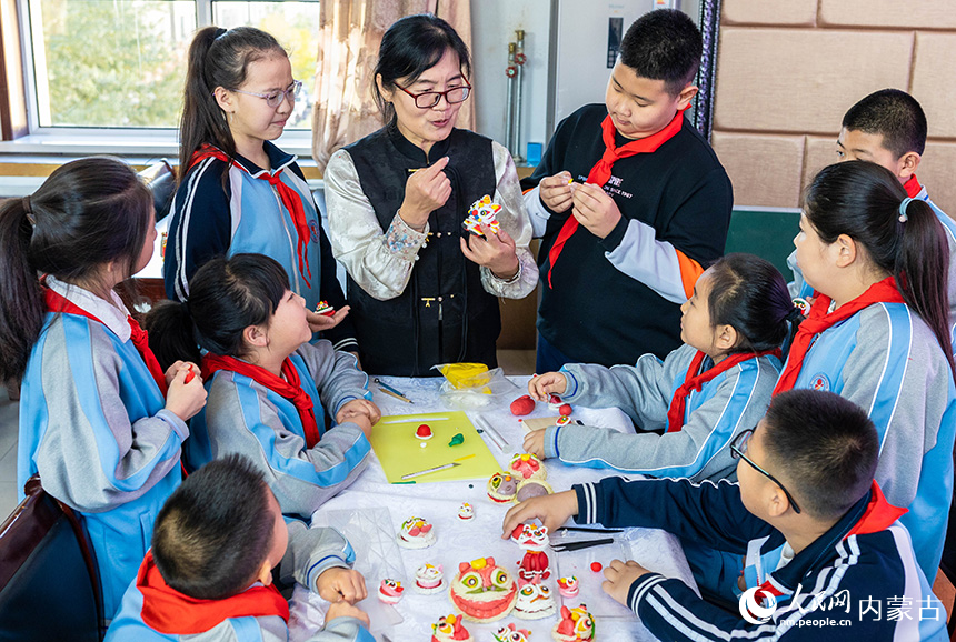 呼和浩特市玉泉区清泉街小学学生在老师的指导下体验面塑狮子的制作技艺。丁根厚摄