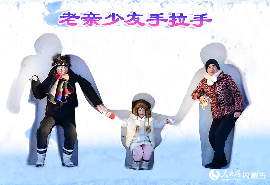 12月12日,游客在满洲里“冰雪童谣”主题乐园与一处雪雕墙互动。王正摄