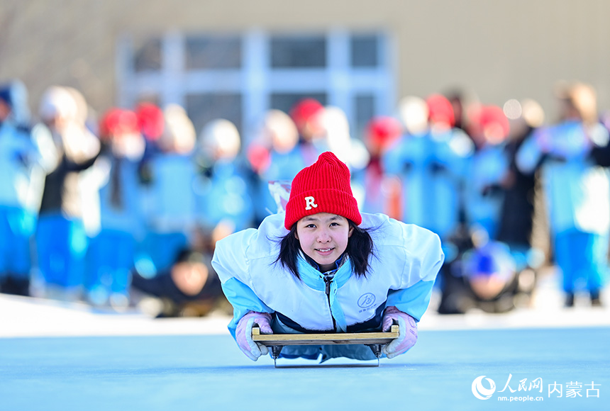 呼倫貝爾市海拉爾區健康街小學學生在校園冰雪嘉年華中參加助跑俯臥式爬犁運動。王正攝