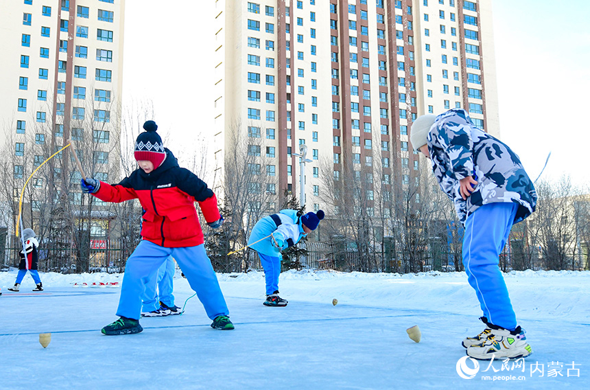 呼倫貝爾市海拉爾區健康街小學學生在校園冰雪嘉年華中參加抽冰尜運動。王正攝