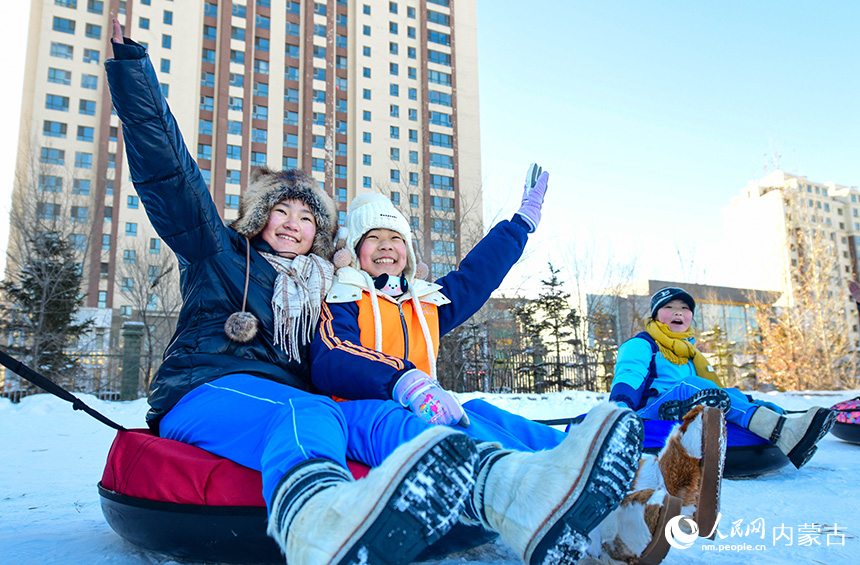 呼倫貝爾市海拉爾區健康街小學學生在校園冰雪嘉年華中參加拉雪圈接力運動。王正攝