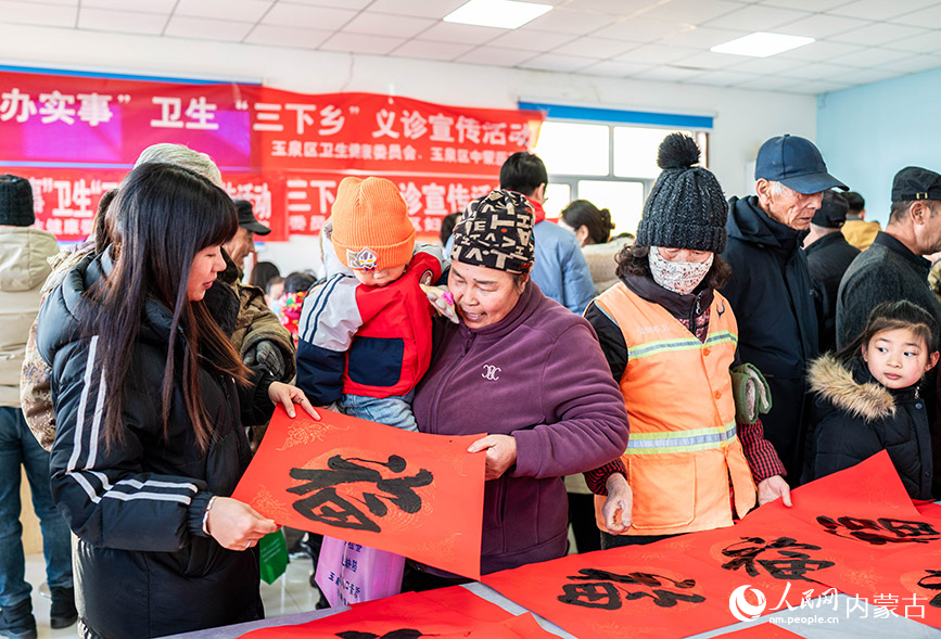 1月18日，志愿者在呼和浩特市玉泉区“三下乡”活动现场为群众赠送新春福字、春联。丁根厚摄