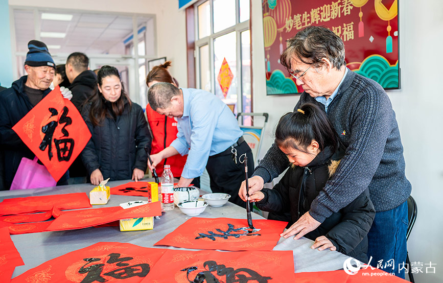 1月18日，志愿者在呼和浩特市玉泉“三下乡”活动现场教小朋友书写春字。丁根厚摄