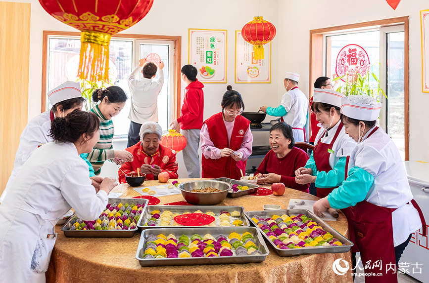 1月20日，志愿者与老人们在呼和浩特市玉泉区民政局迎新春主题活动现场一起包饺子。丁根厚摄