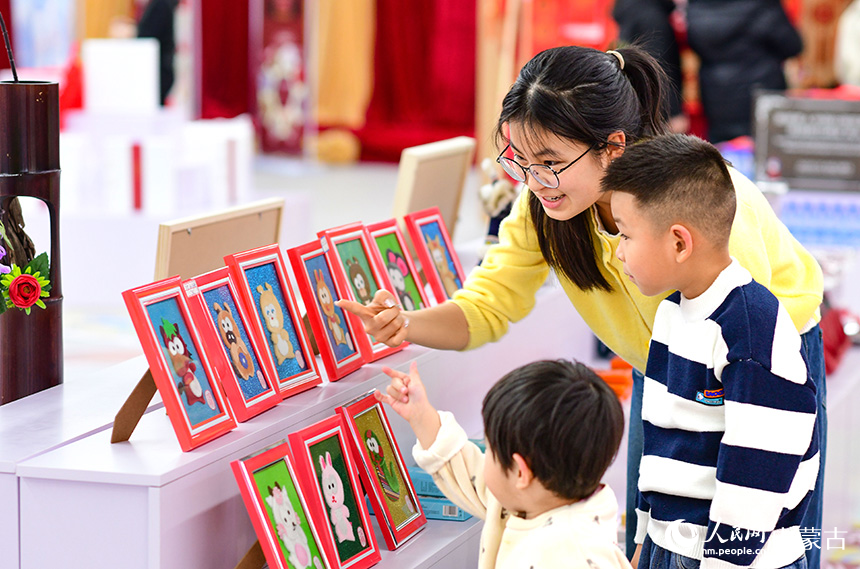 小朋友在“我们的非遗中国年”系列活动上观赏非遗布贴画作品。王正摄