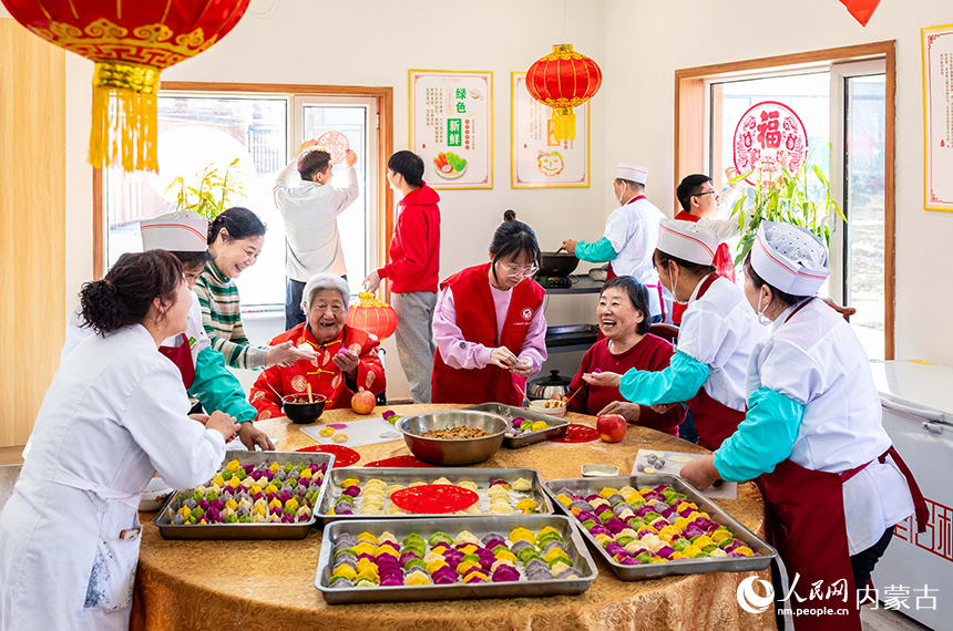 志愿者与老人们在呼和浩特市玉泉区民政局迎新春主题活动现场一起包饺子。丁根厚摄