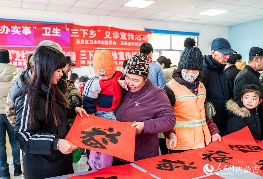 志愿者在呼和浩特市玉泉区前毛道村为群众赠送新春福字、春联。丁根厚摄