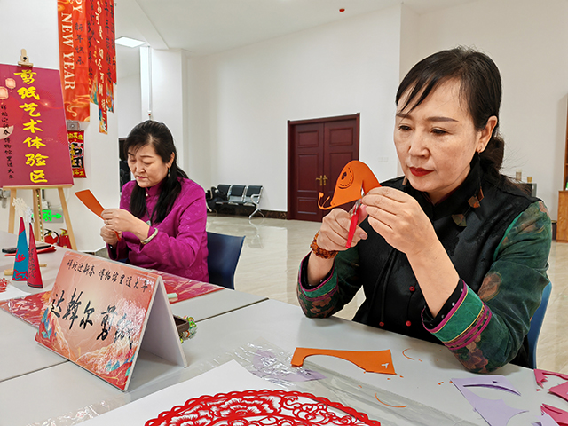 达斡尔剪纸体验区非遗传承人们专注展技艺。郑明摄