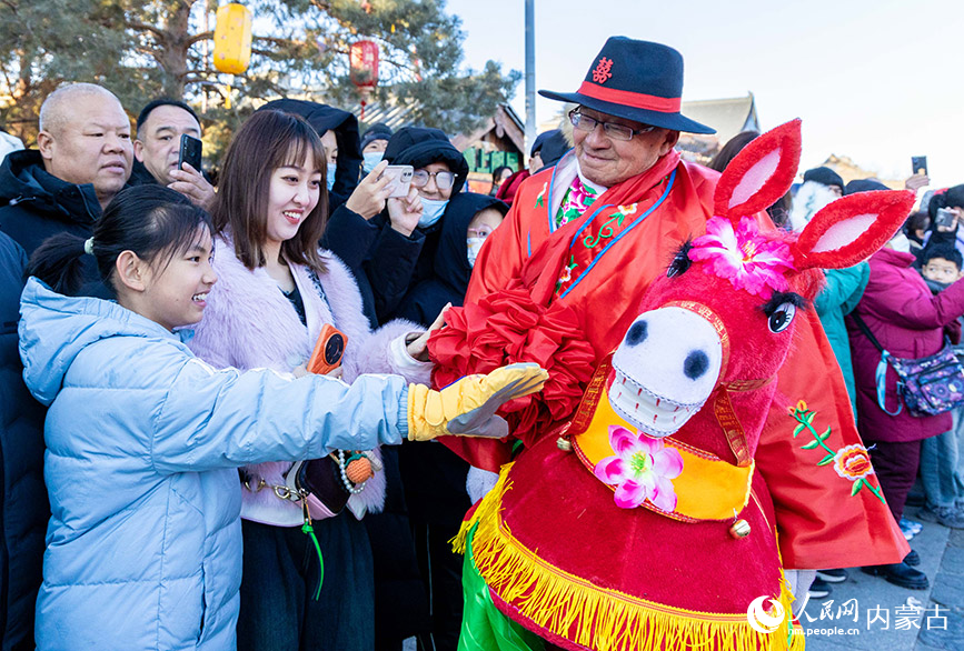 2025年2月3日，民间艺人在呼和浩特新春文化庙会上与游客互动。丁根厚摄