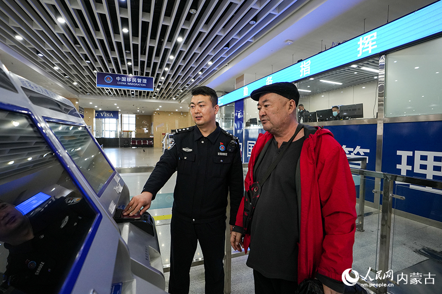 二連出入境邊防檢查站移民管理警察幫助旅客打印通關憑証。郭鵬杰攝