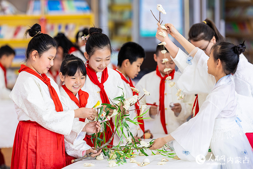 呼和浩特市玉泉区通顺街小学的少先队员们将当地清明时节的特色面塑“寒燕”悬挂枝头，寓意春燕归来。丁根厚摄