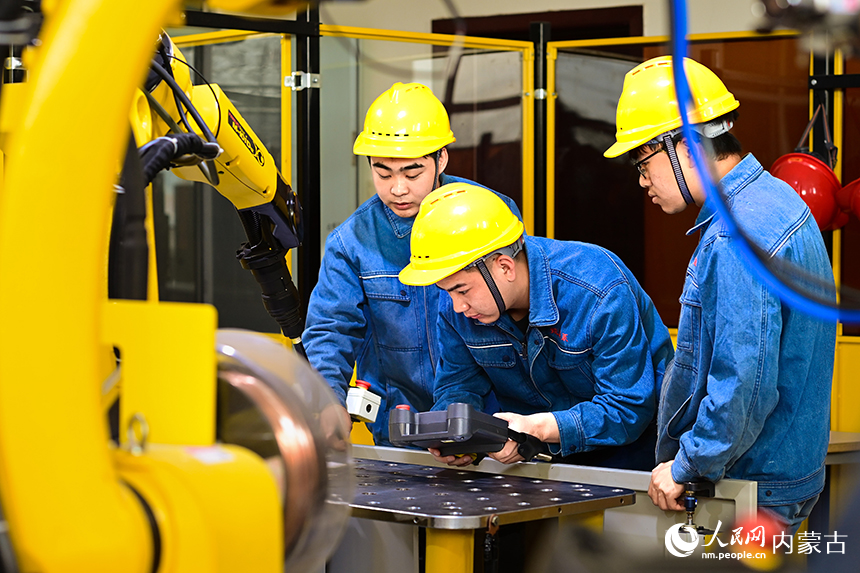 內蒙古機電職業技術學院學生在機器人焊接實訓基地參加實訓學習。王正攝
