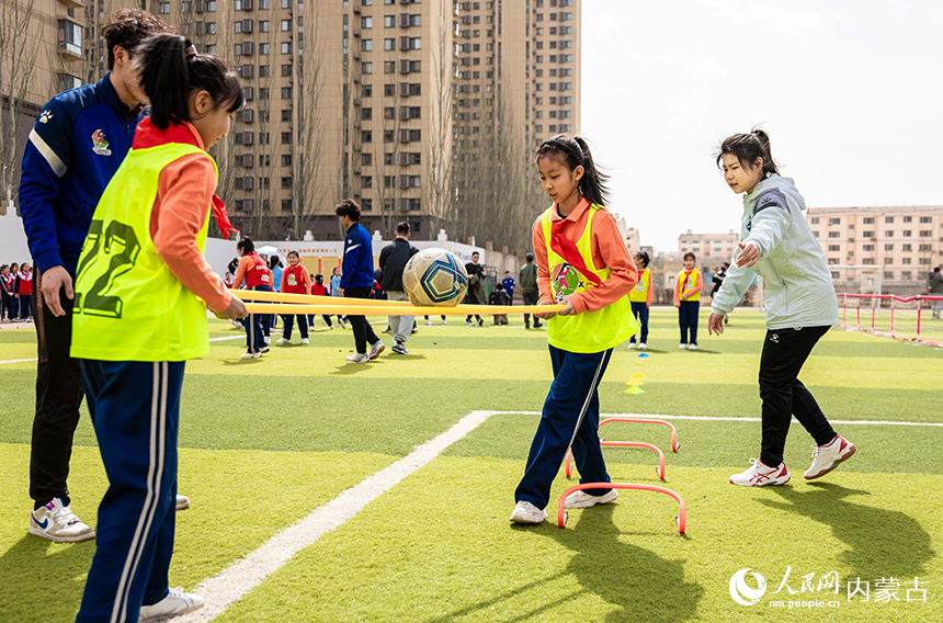 呼和浩特市玉泉區石東路小學女足隊員在女孩足球節活動現場參加趣味足球游戲。丁根厚攝