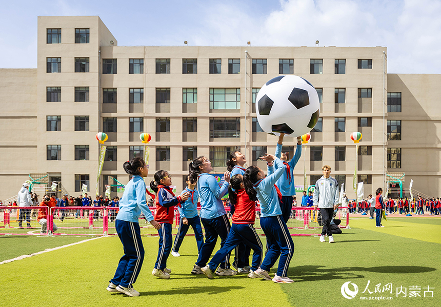 呼和浩特市玉泉区石东路小学女足队员在女孩足球节活动现场参加趣味足球游戏。丁根厚摄