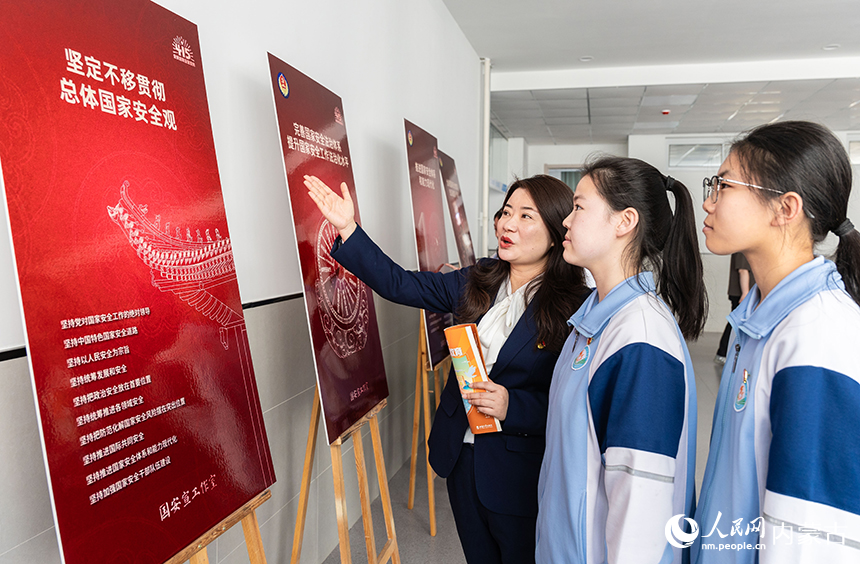 呼和浩特市第二十七中學的青年教師和團員學生在參觀全民國家安全教育日宣傳海報。丁根厚攝