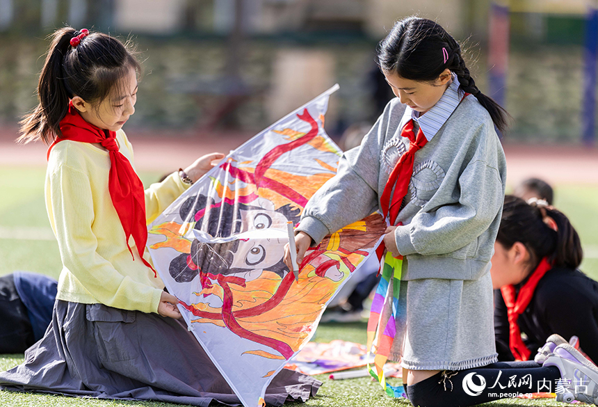 呼和浩特市玉泉區五塔寺東街小學學生在操場上彩繪風箏。丁根厚攝