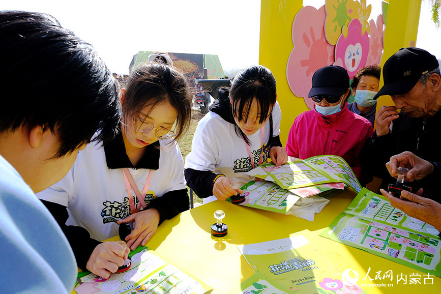 “花漾青城”2025呼和浩特賞花季系列文旅活動開啟，市民正在開幕式現場集章打卡。人民網記者 劉藝琳攝