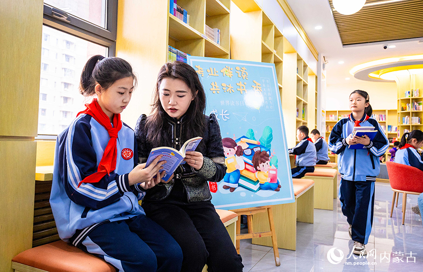 呼和浩特市玉泉區南柴火市街小學青年教師在校園圖書館輔導學生們閱讀。丁根厚攝