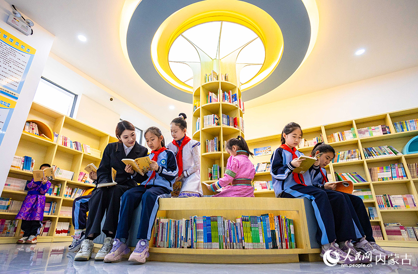 呼和浩特市玉泉區南柴火市街小學青年教師在校園圖書館輔導學生們閱讀。丁根厚攝